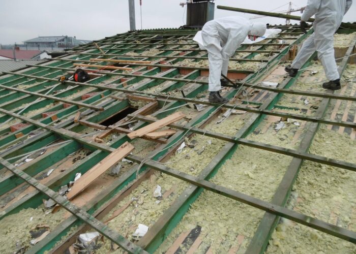 Mitarbeiter*innen arbeiten mit Schutzanzügen an Dach mit Asbestbefall